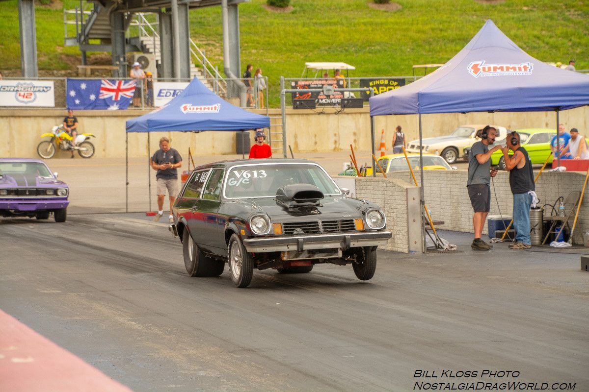 A black car is driving down a race track next to a purple car.