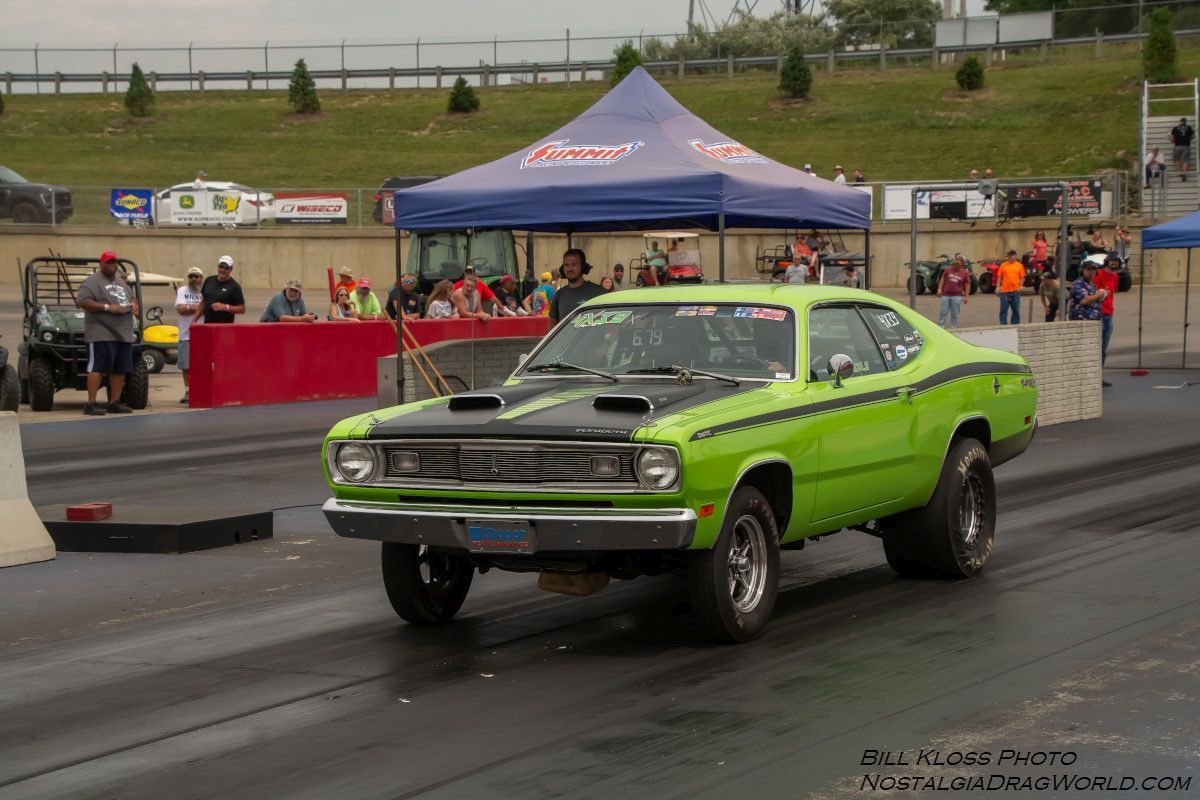 A green car is driving down a race track.