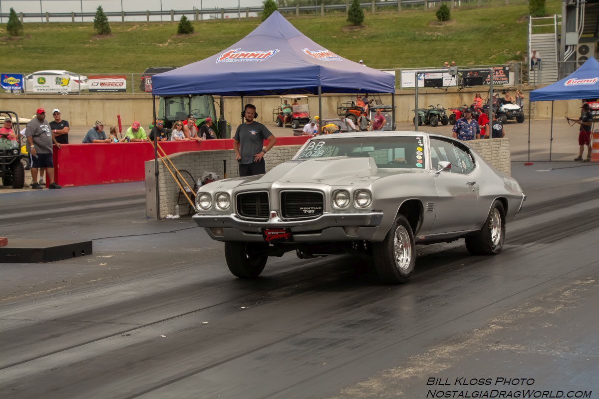 A silver car is driving down a race track