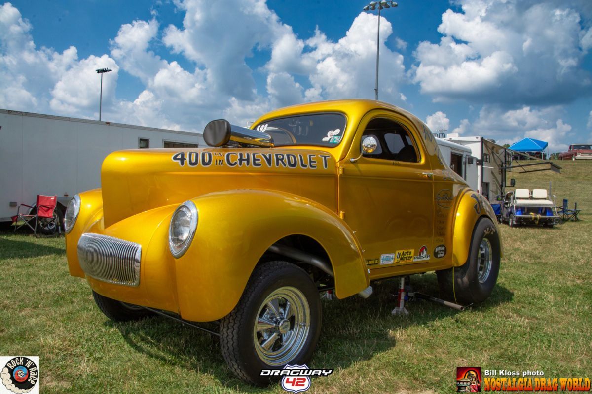 A yellow chevrolet car is parked in the grass at a car show.