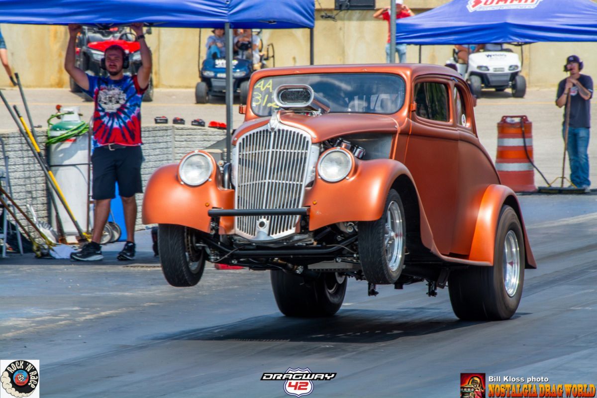 A man is standing next to a car on a race track.