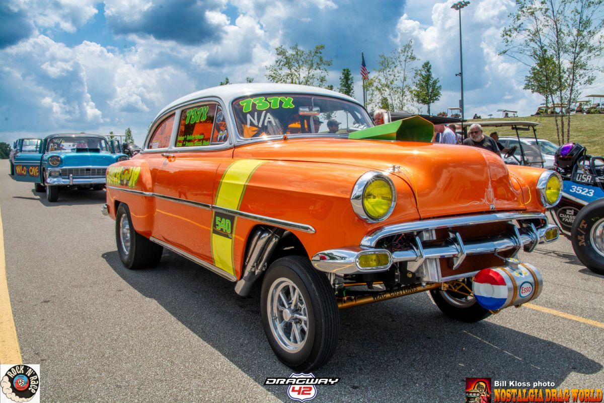 An orange car with yellow stripes is parked on the side of the road.