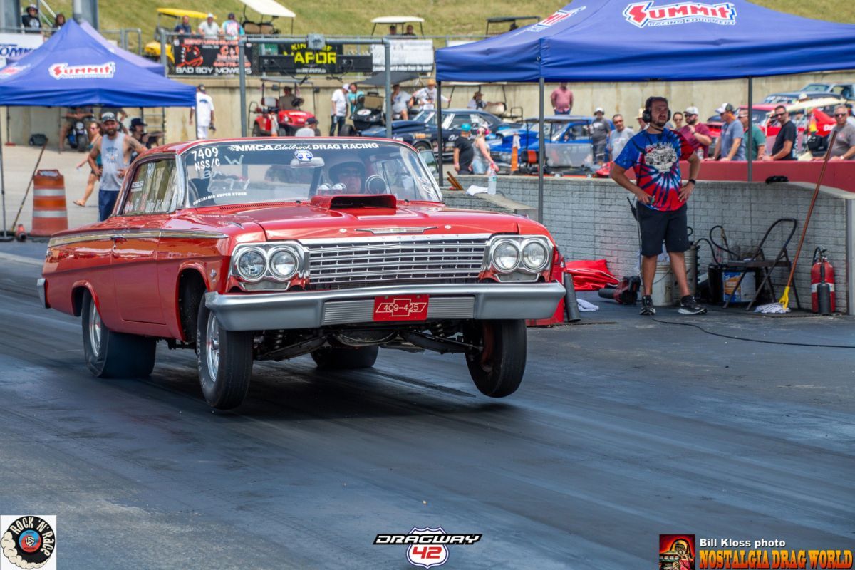 A red car is driving down a race track.