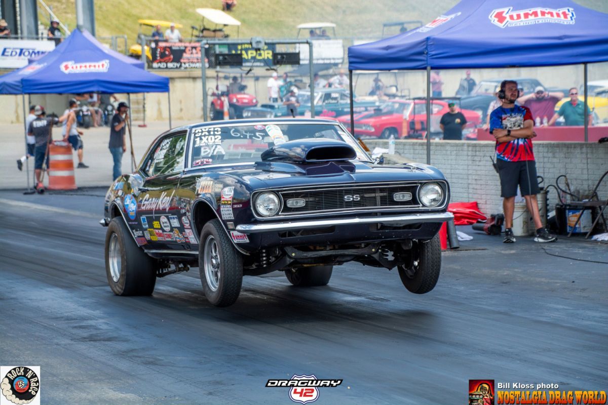 A black muscle car is driving down a race track.