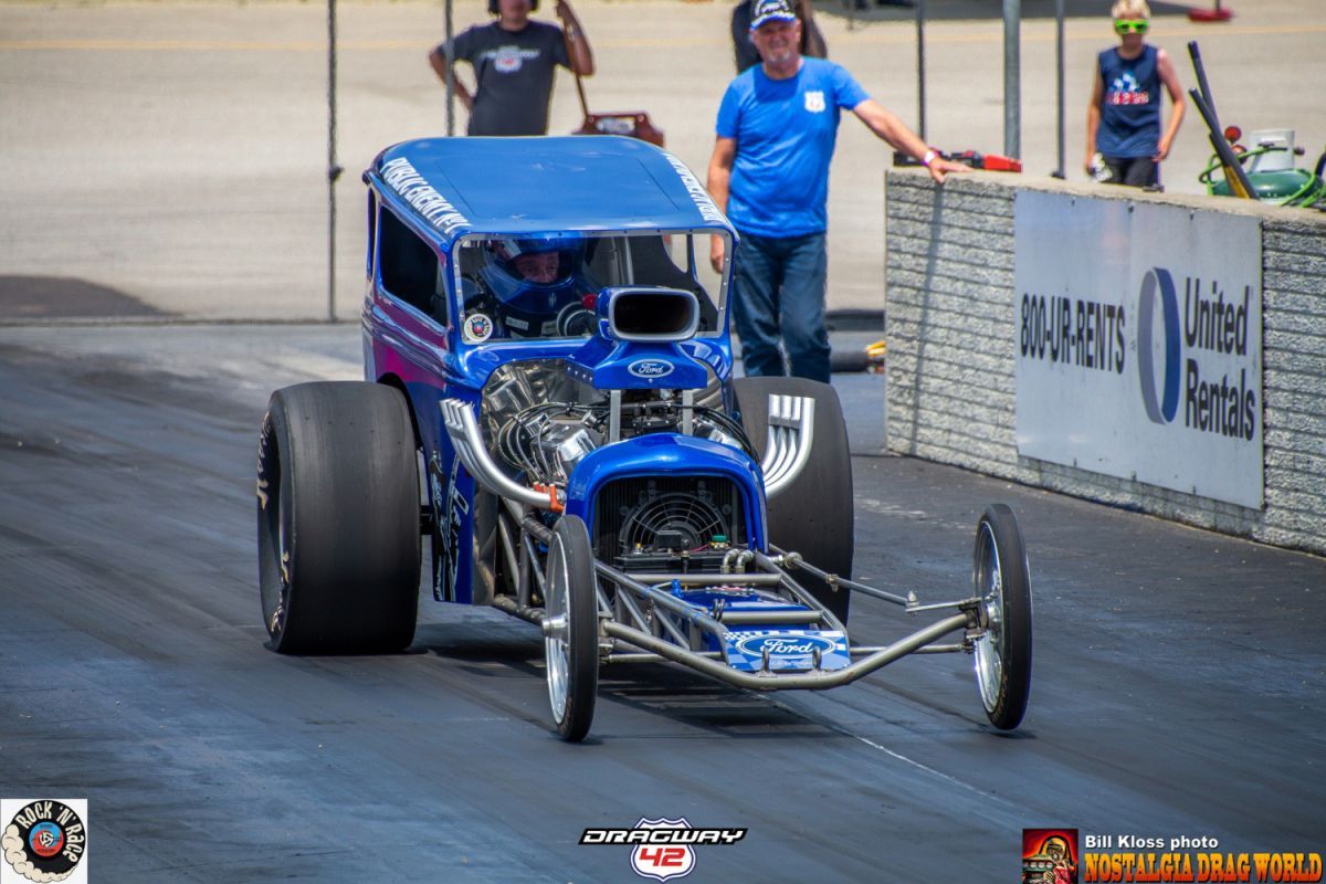 A blue race car is driving down a race track.