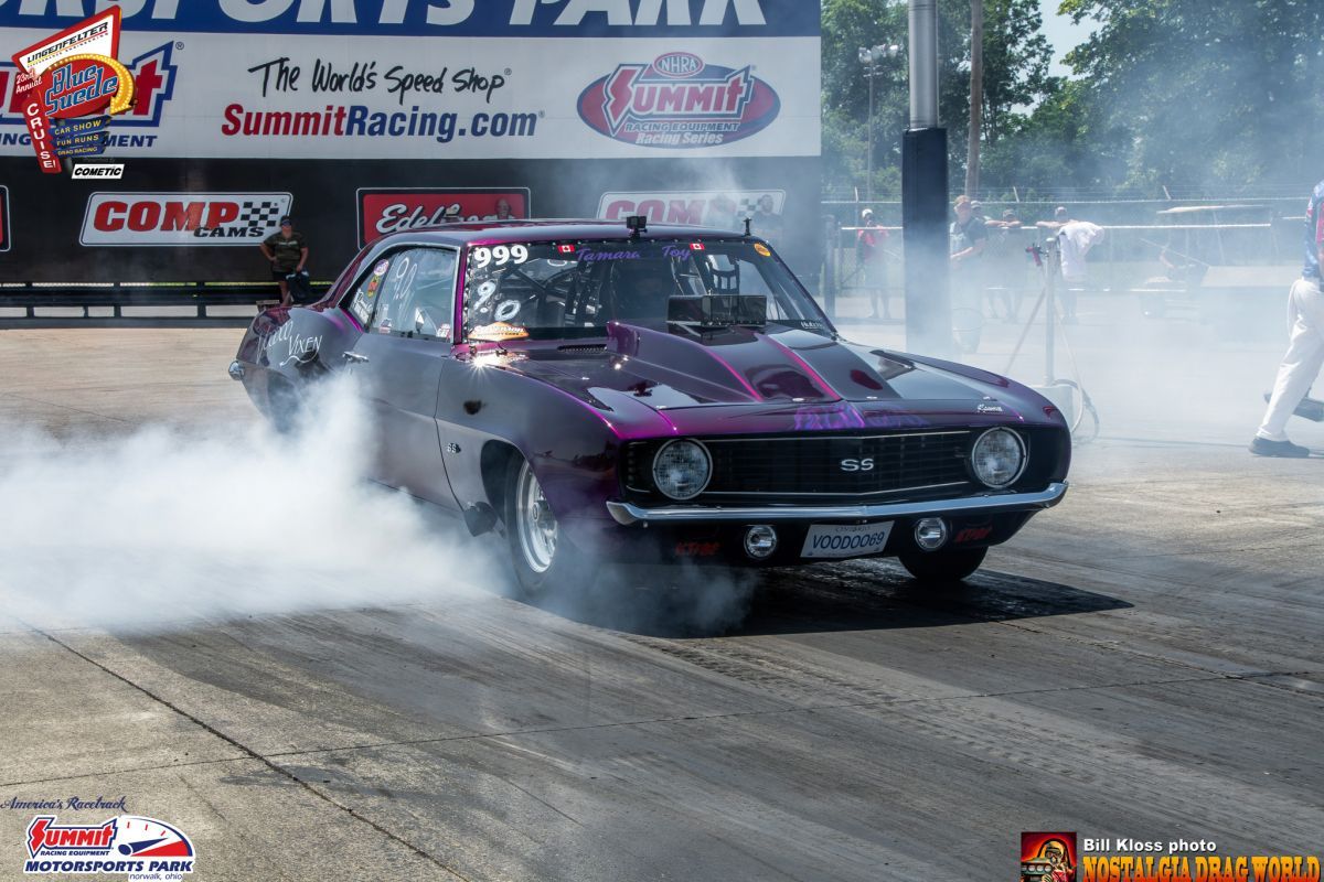 A purple car is doing a burnout on a race track.