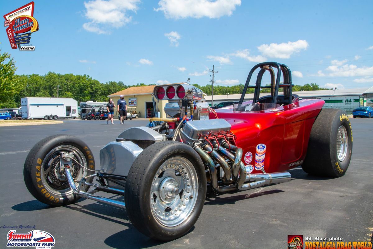 A red race car is parked in a parking lot.