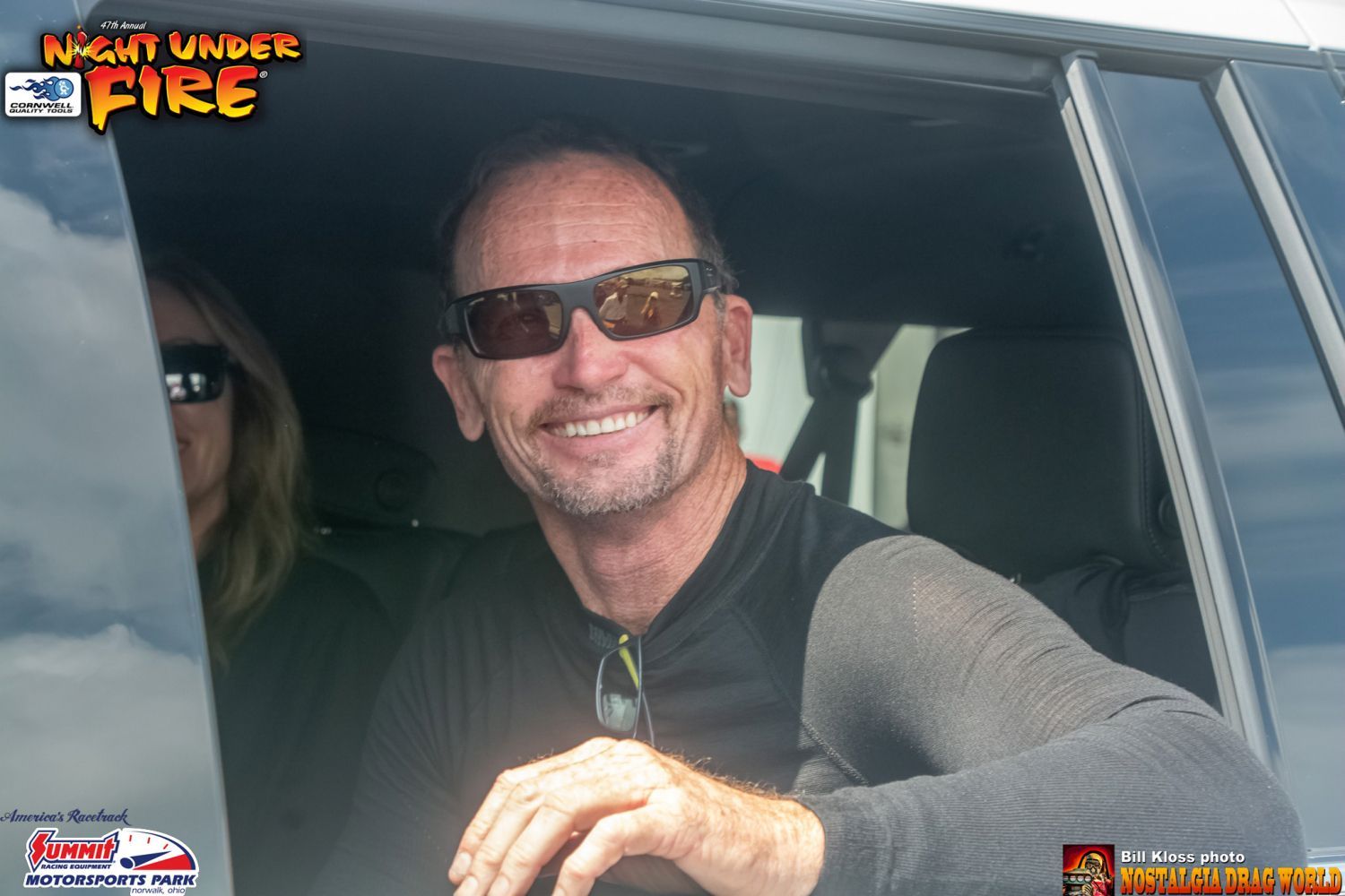 A man wearing sunglasses is smiling while sitting in a car ..