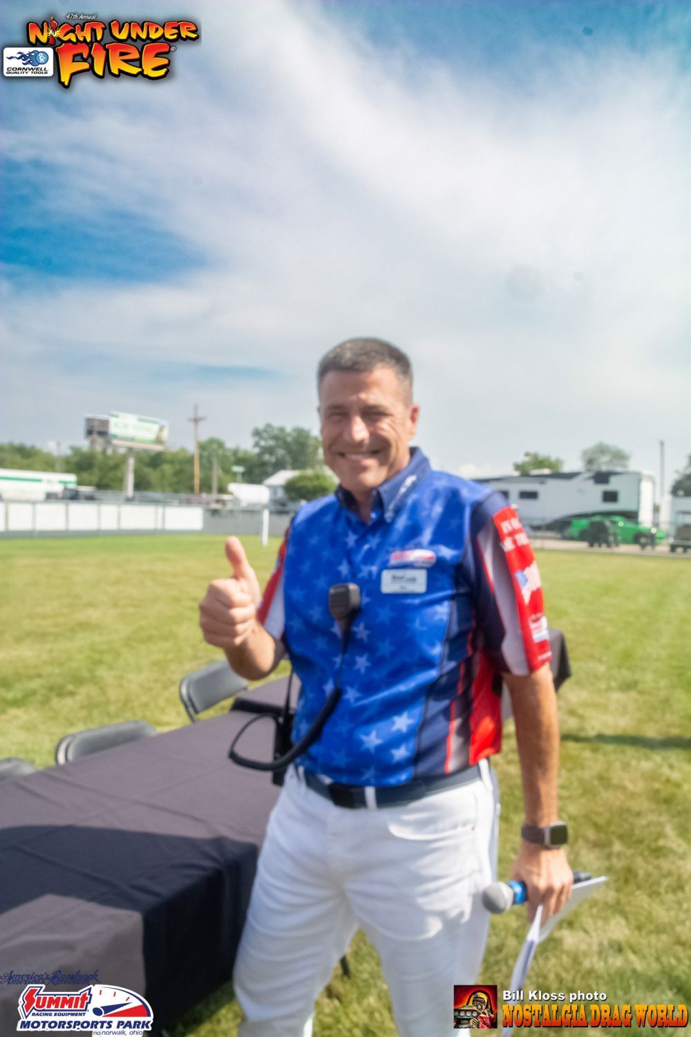 A man in a blue and red shirt is giving a thumbs up
