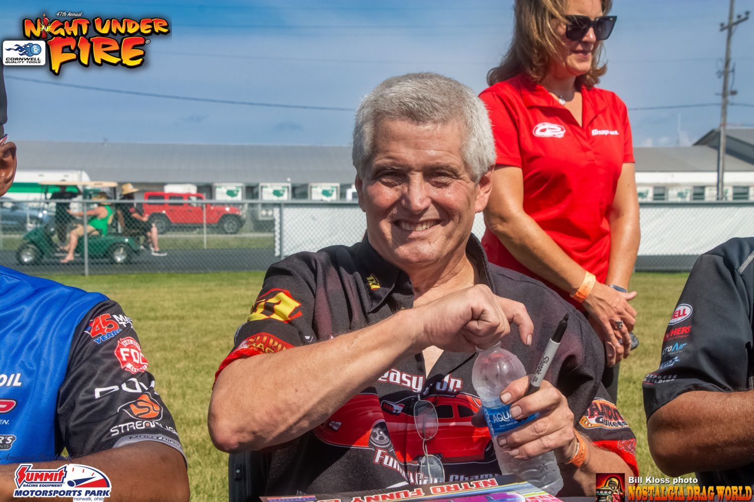 A man in a wheelchair is smiling while holding a bottle of water.