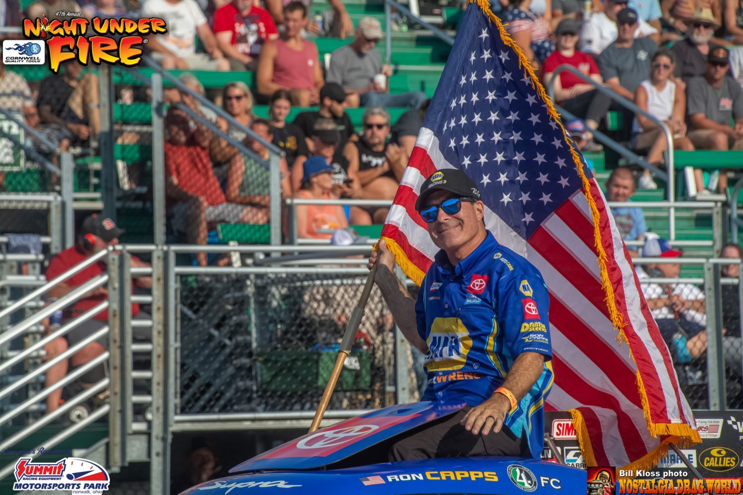 A man in a blue shirt is holding an american flag