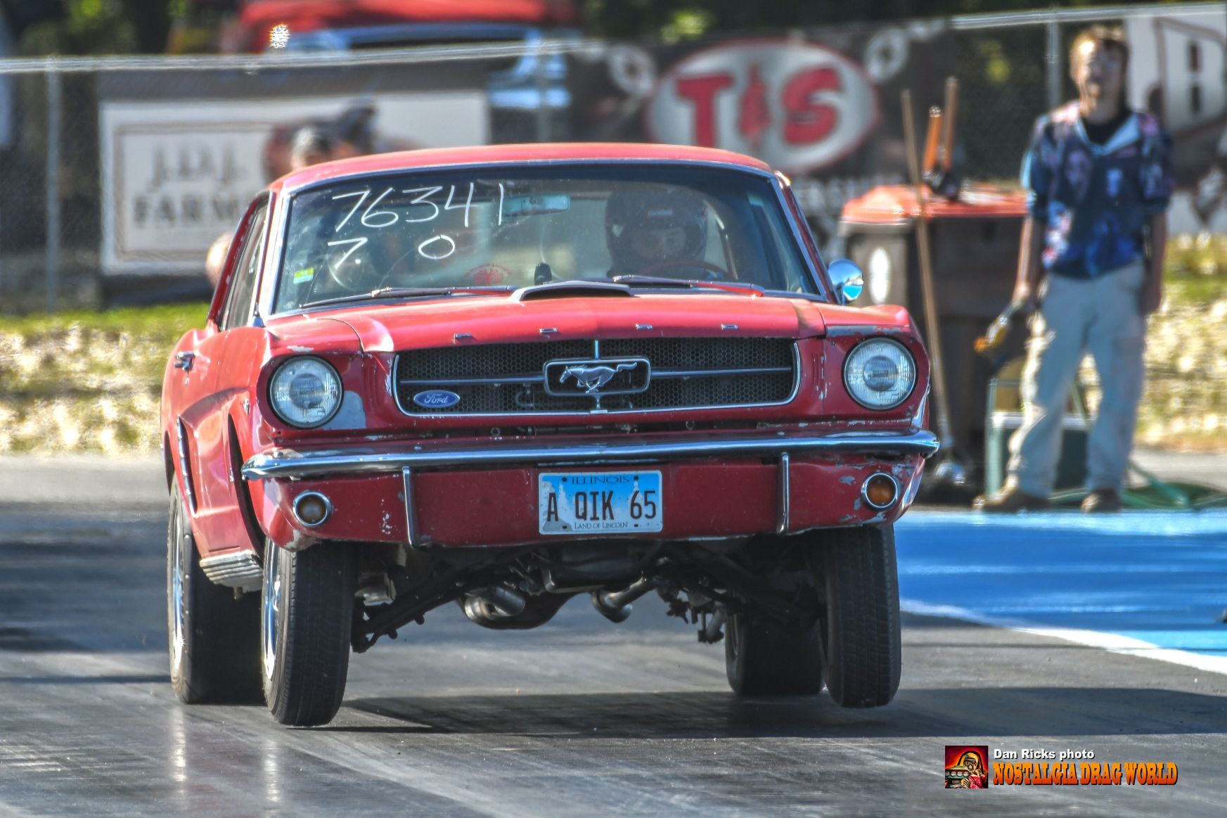 A red ford mustang is driving down a race track.