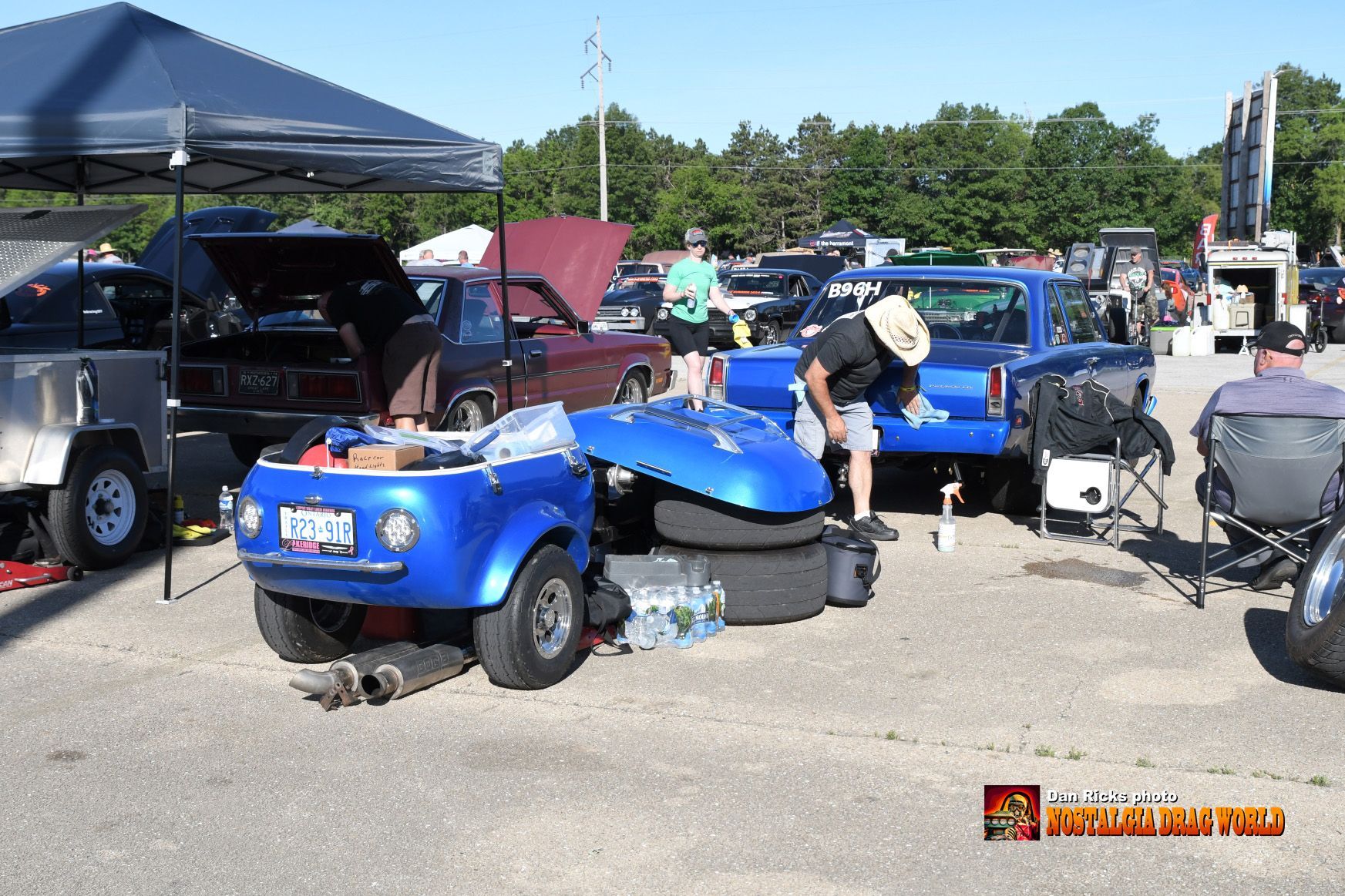 A man is working on a blue golf cart in a parking lot