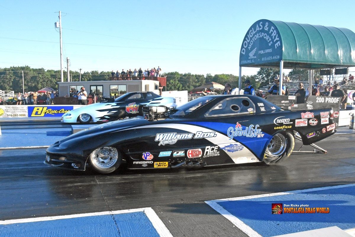 A black and blue drag race car is on a track