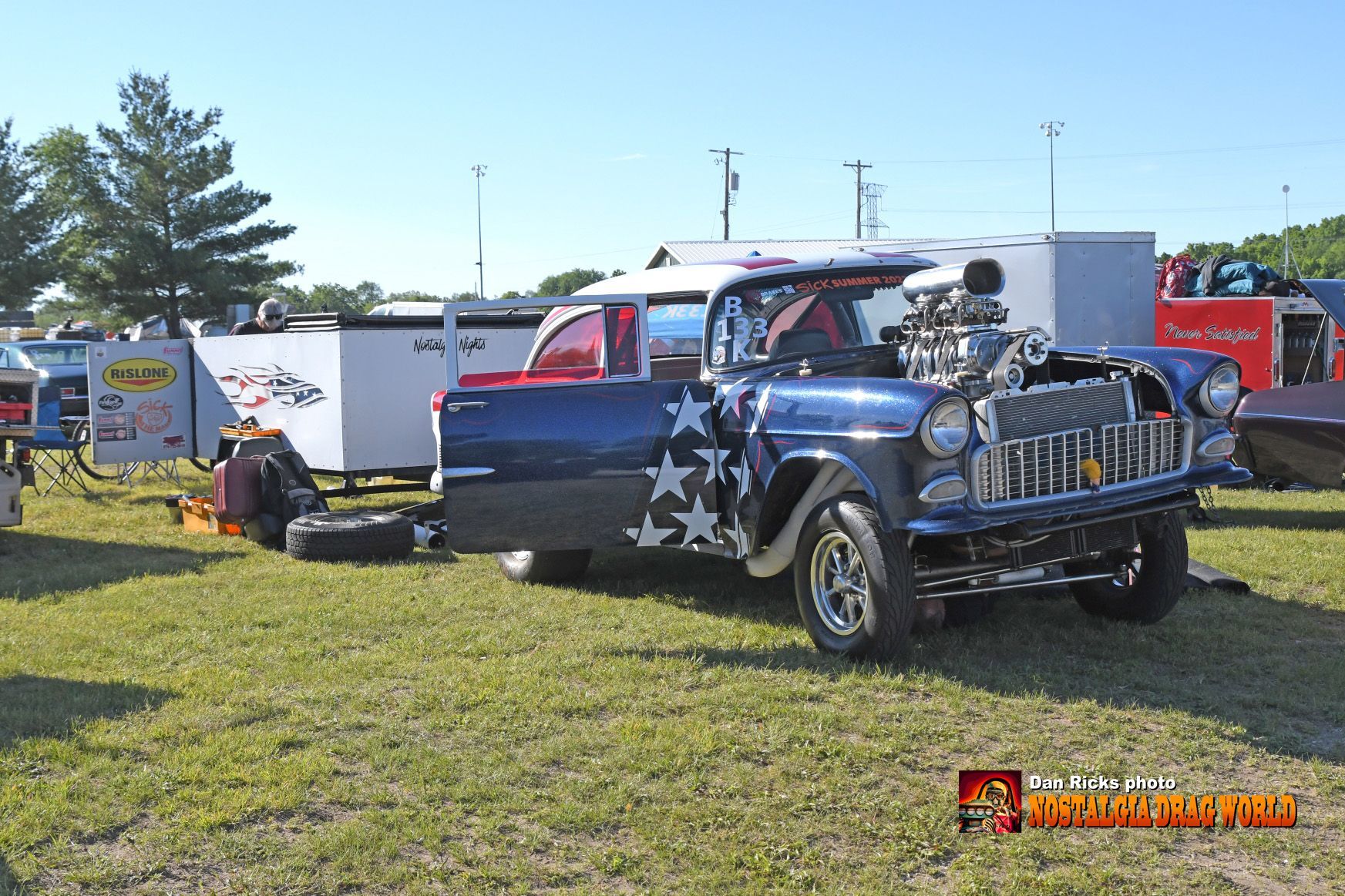 A blue truck is parked in a grassy field with a trailer attached to it ..