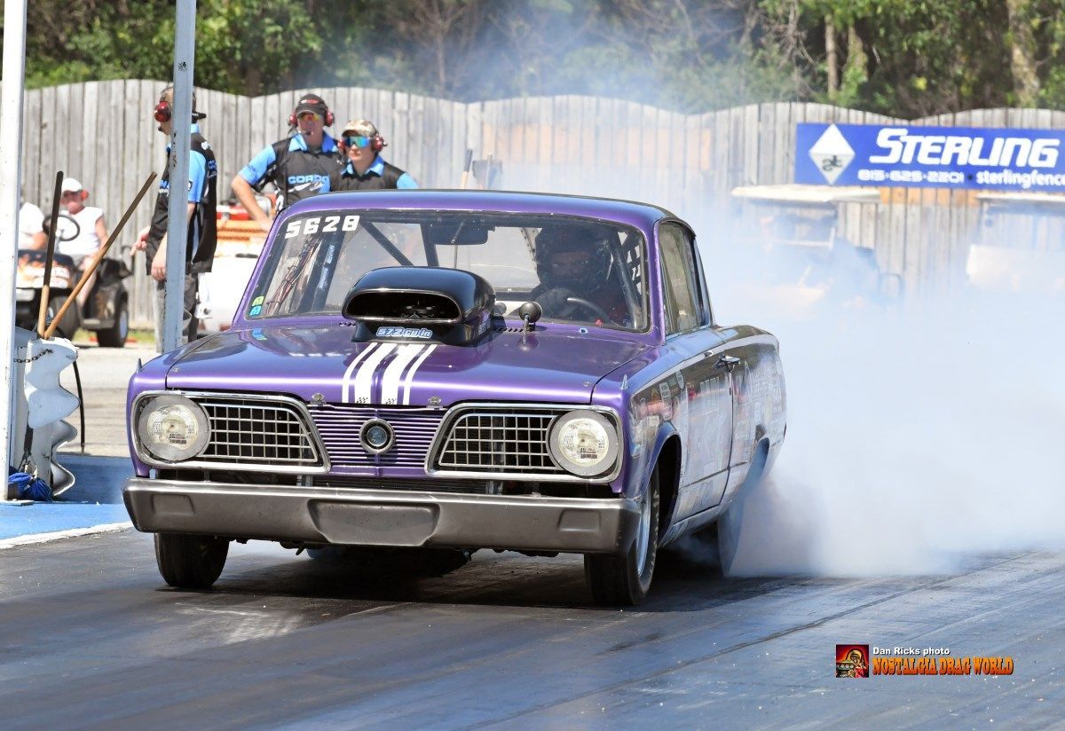 A purple car is doing a burnout on a race track.