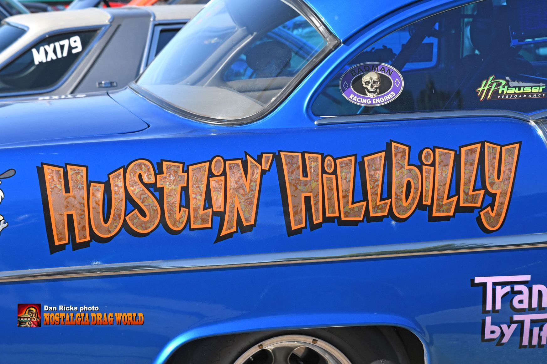 A blue car with hustlin hillbilly written on the side