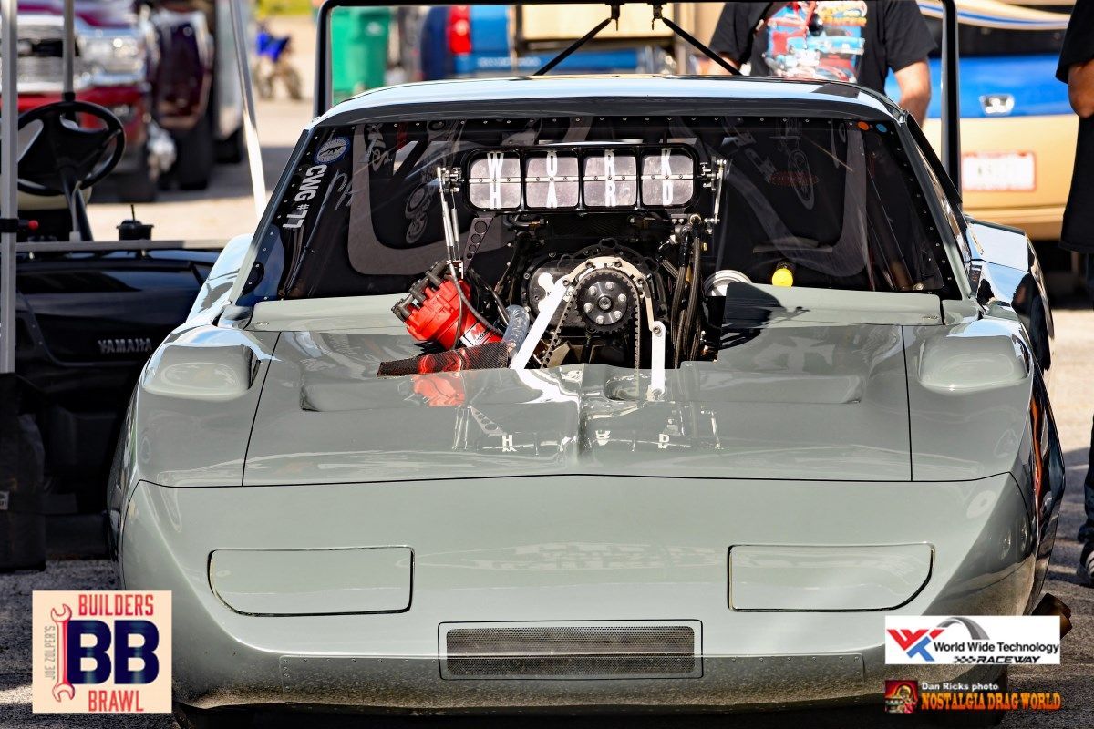 A race car with the hood open is parked in a parking lot.