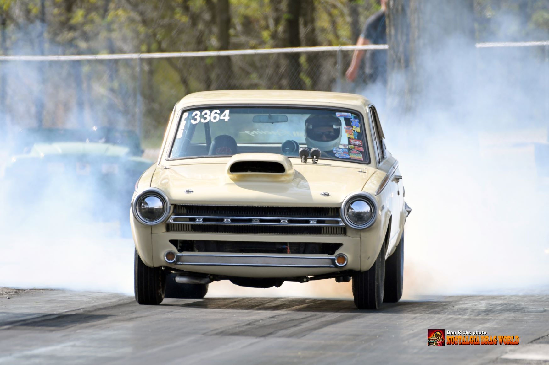 A car with the number 3364 on the windshield is driving down a road.