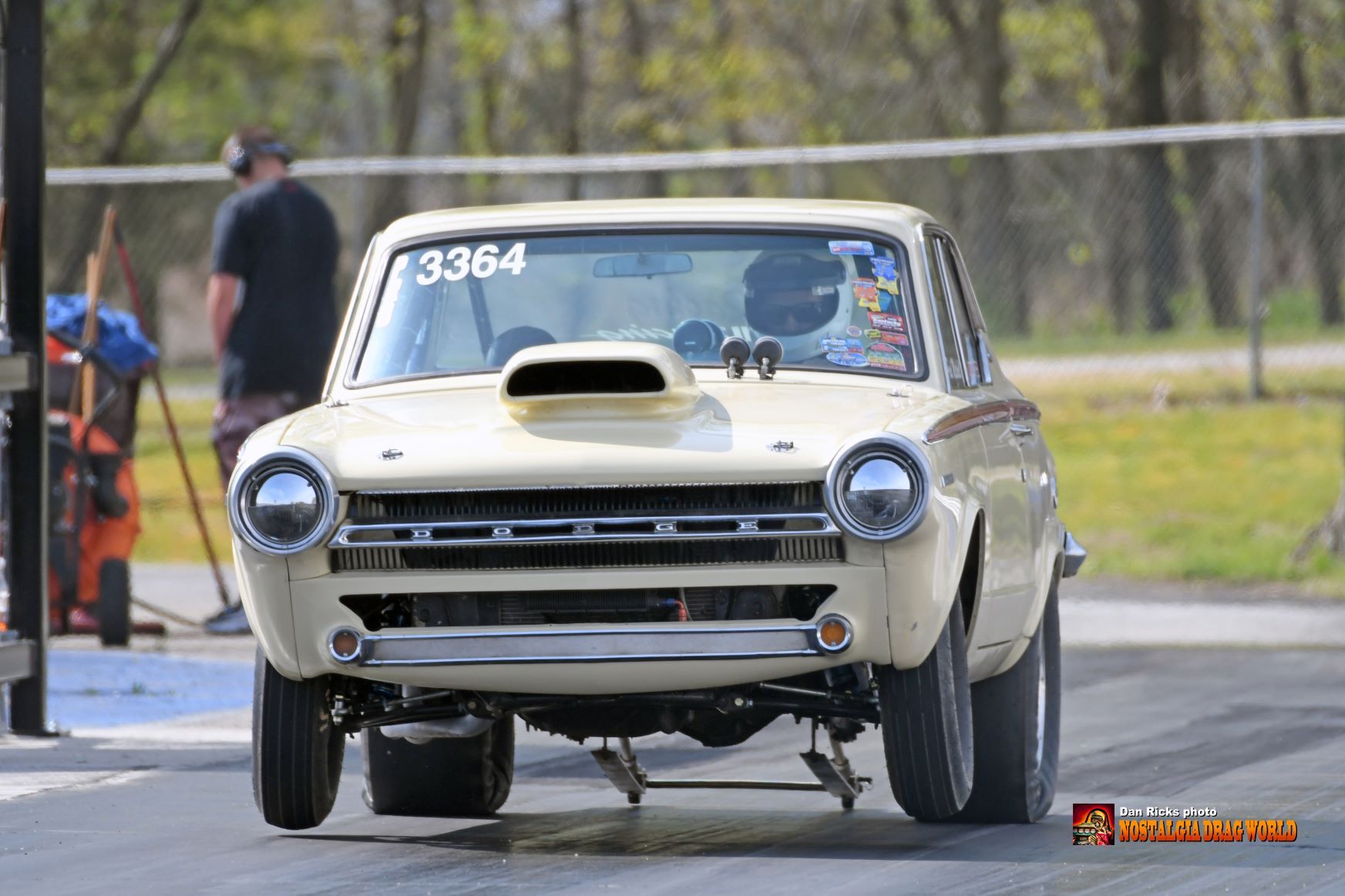 A white car with a hood scoop is driving down a race track.