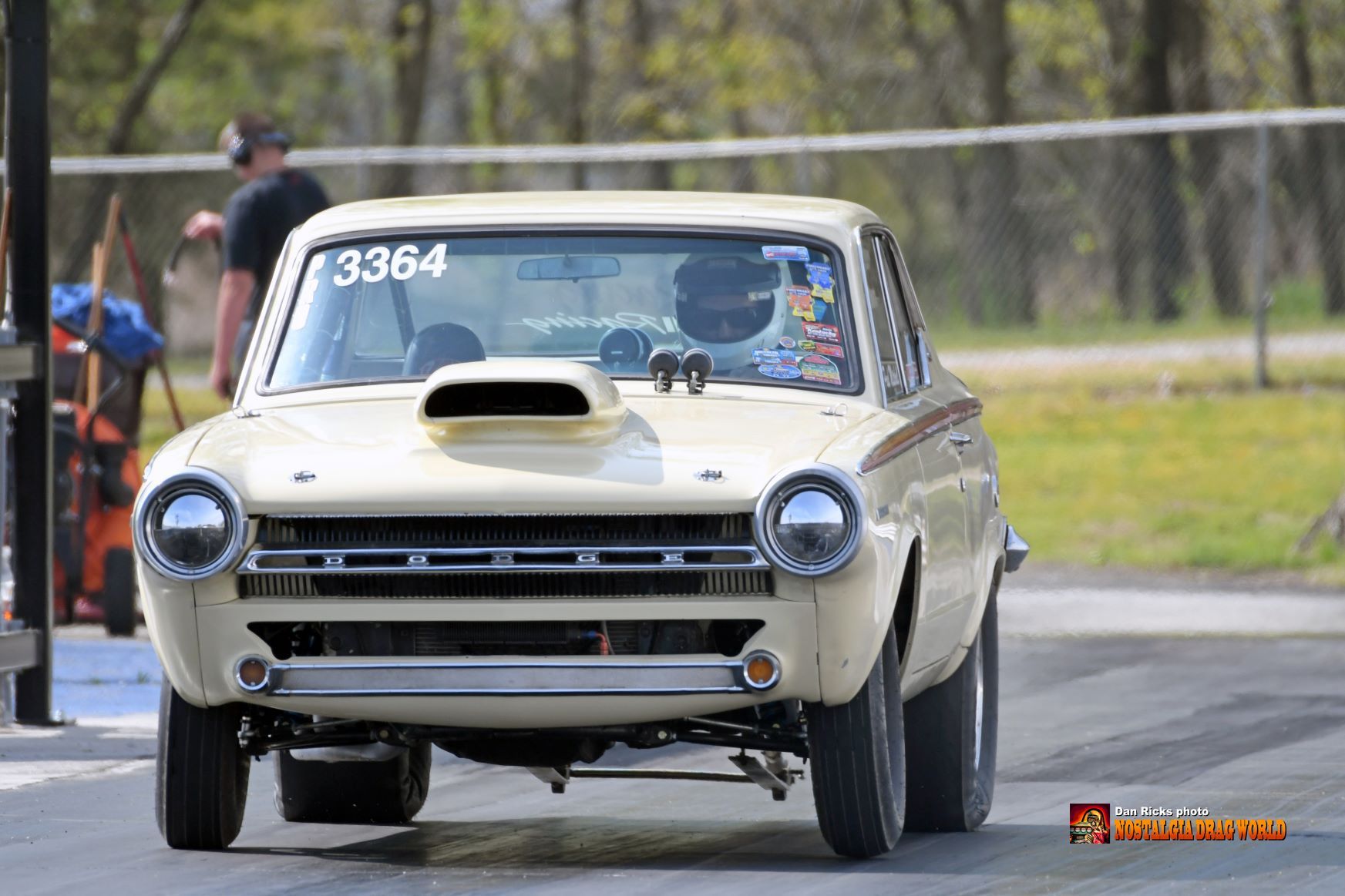 A white car with the number 3364 on the windshield is driving down a road.