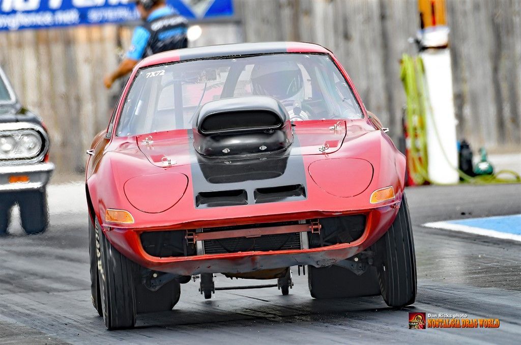 A red corvette is driving down a race track.