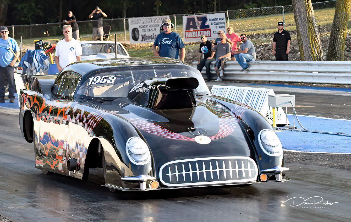 A black race car with the number 1052 on the front is driving down a track.