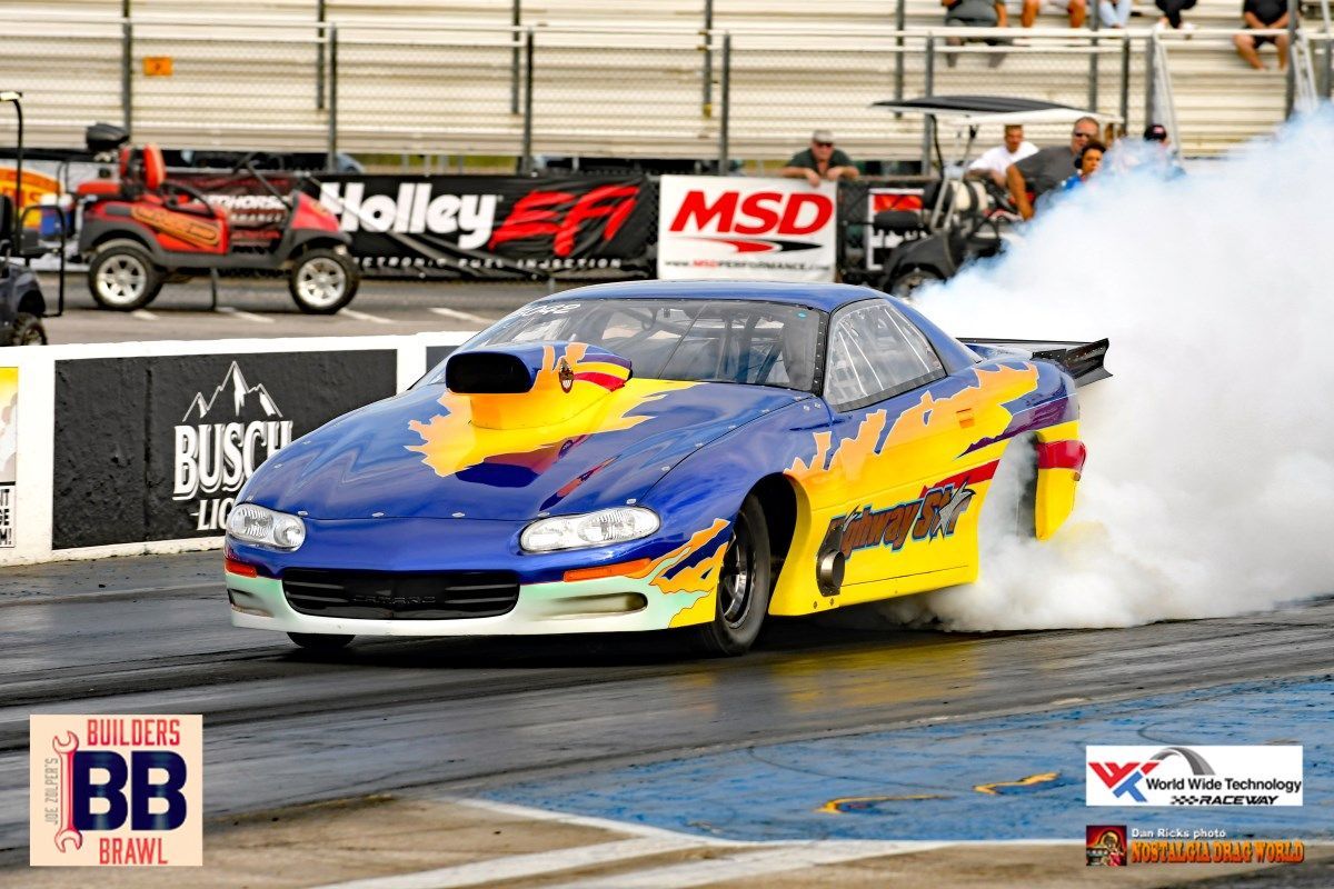 A blue and yellow race car is doing a burnout on a track.