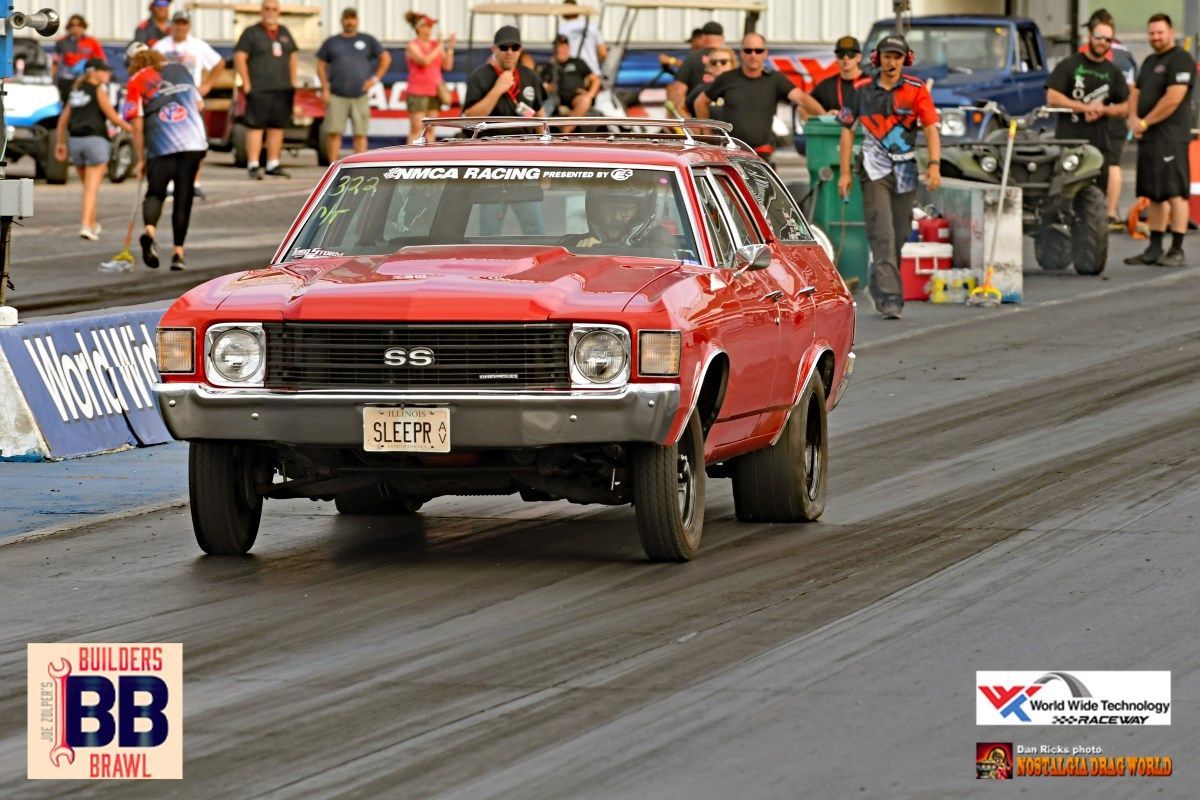 A red car is driving down a track with a sign that says bb on it