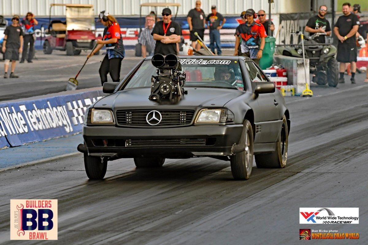 A mercedes is driving down a race track with a bb sign in the background