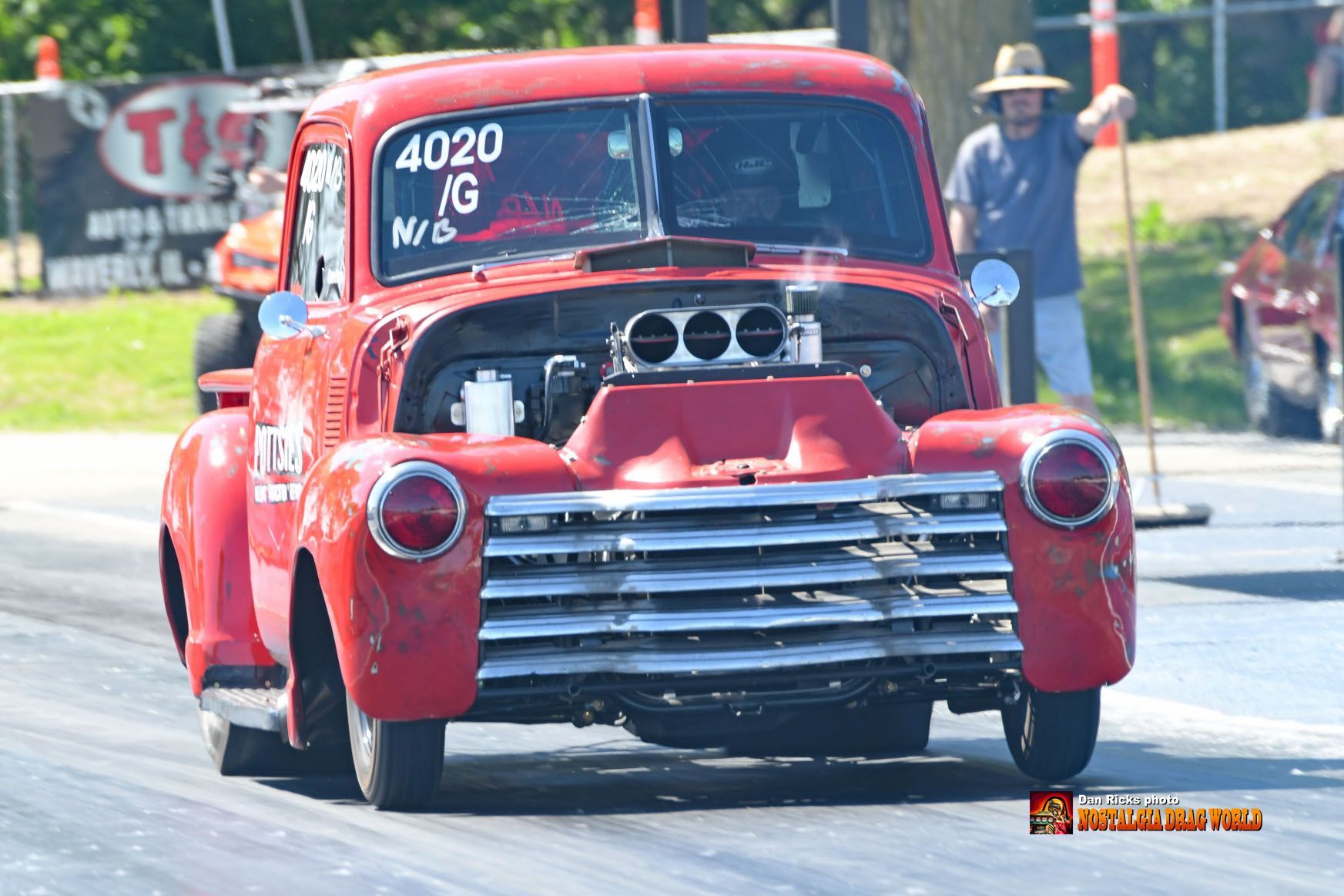 A red car with the number 4020 on the windshield is driving down a race track.