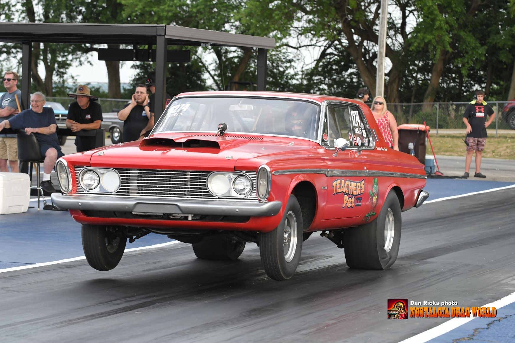 A red muscle car is driving down a race track