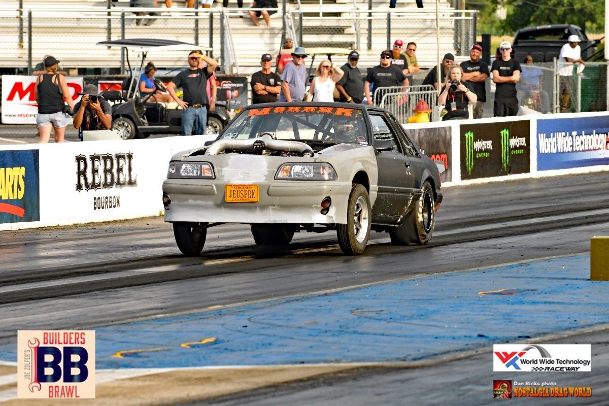 A car is driving down a race track with a sign that says rebel on it