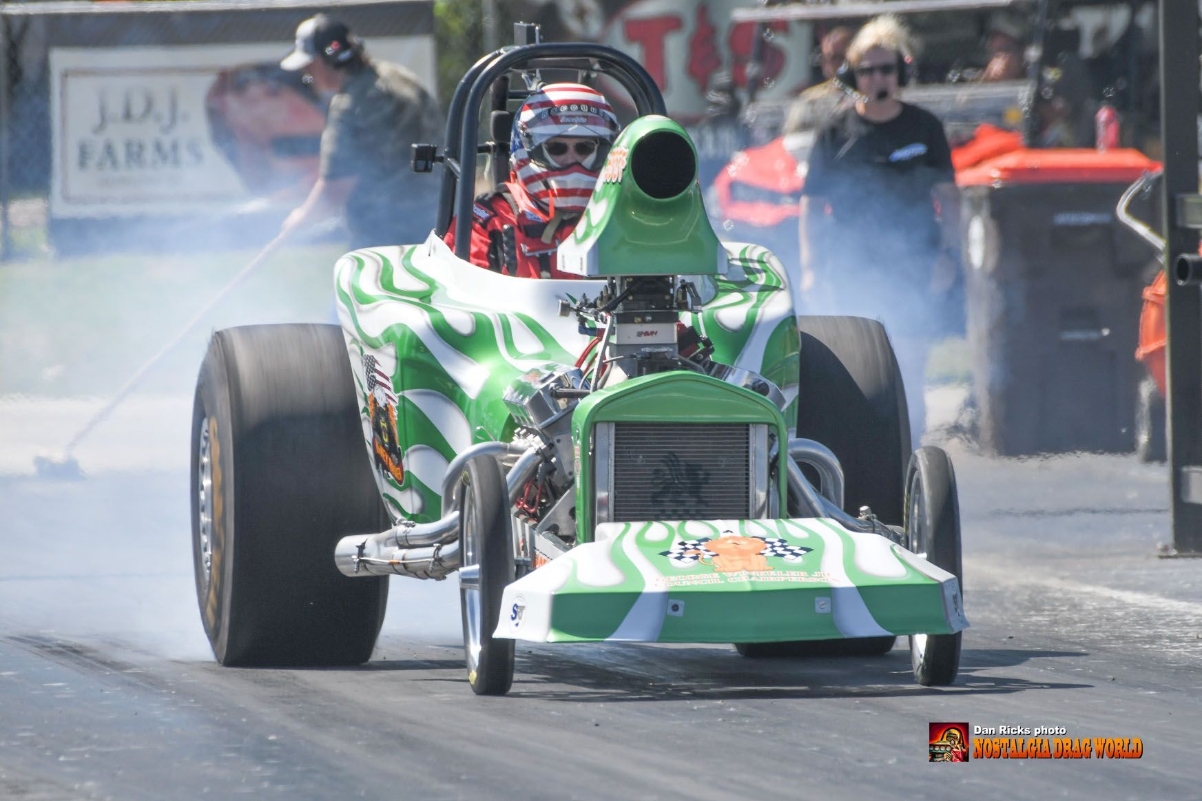 A green and white race car is driving down a track