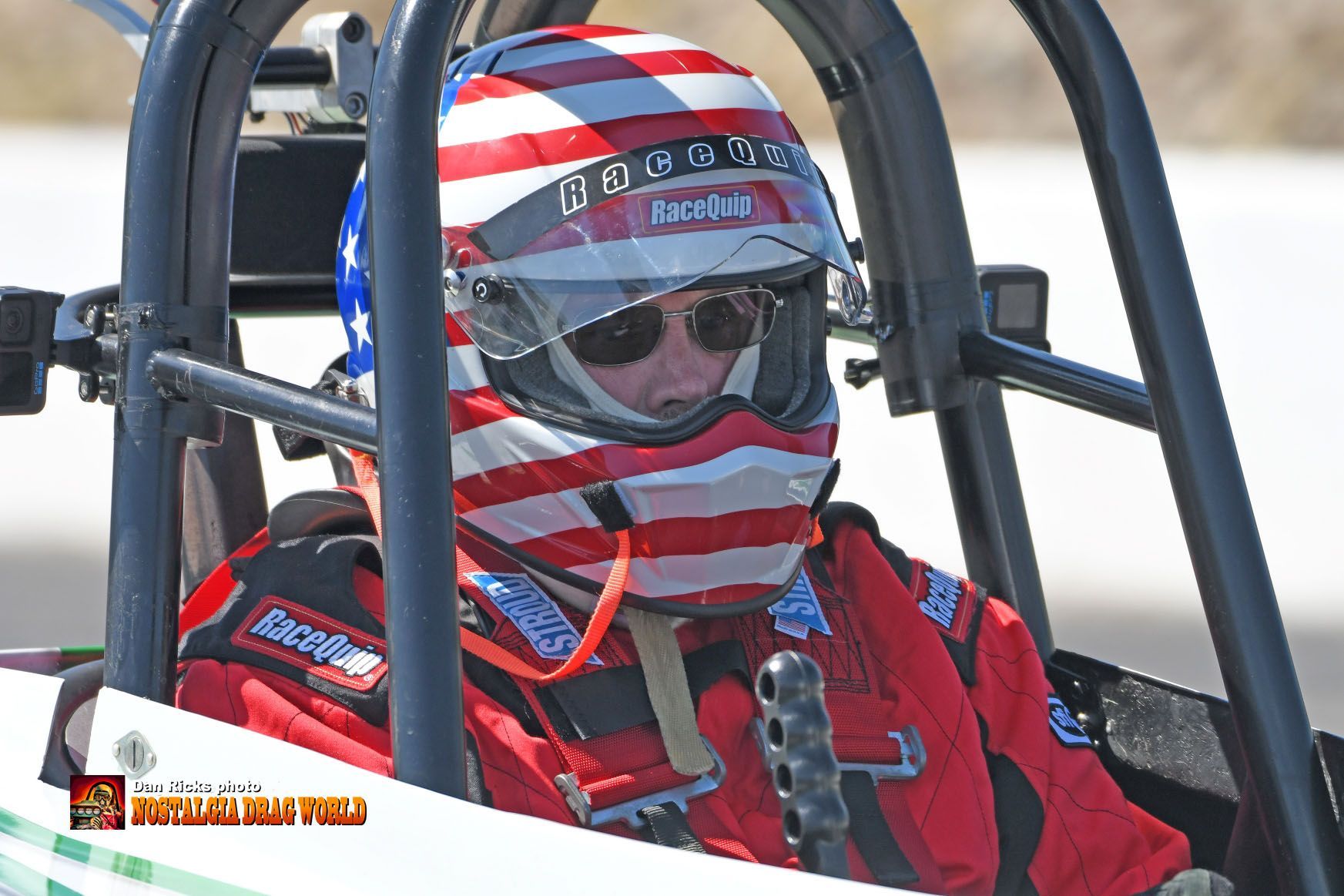 A man wearing an american flag helmet is sitting in a race car