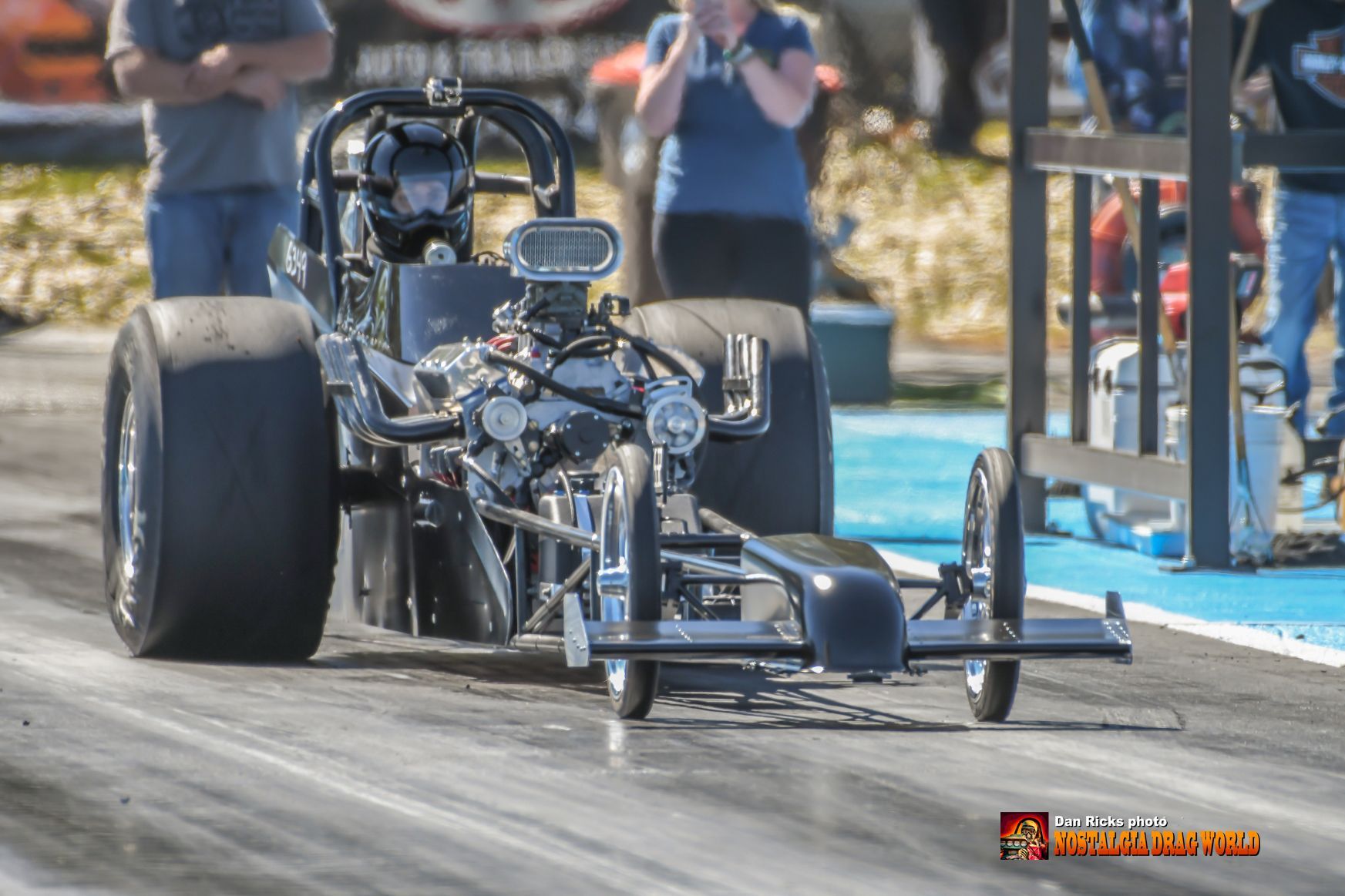 A drag race car is driving down a track.