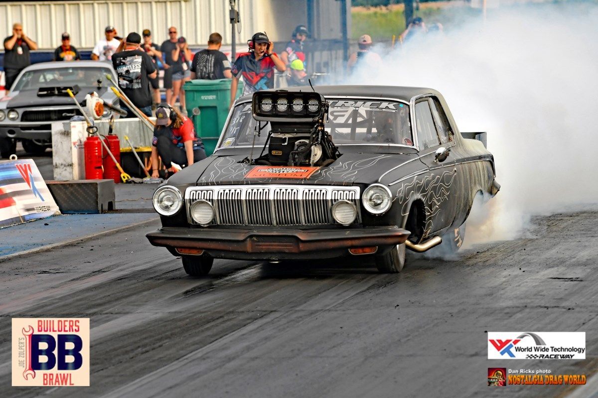 A black car is doing a burnout on a race track.