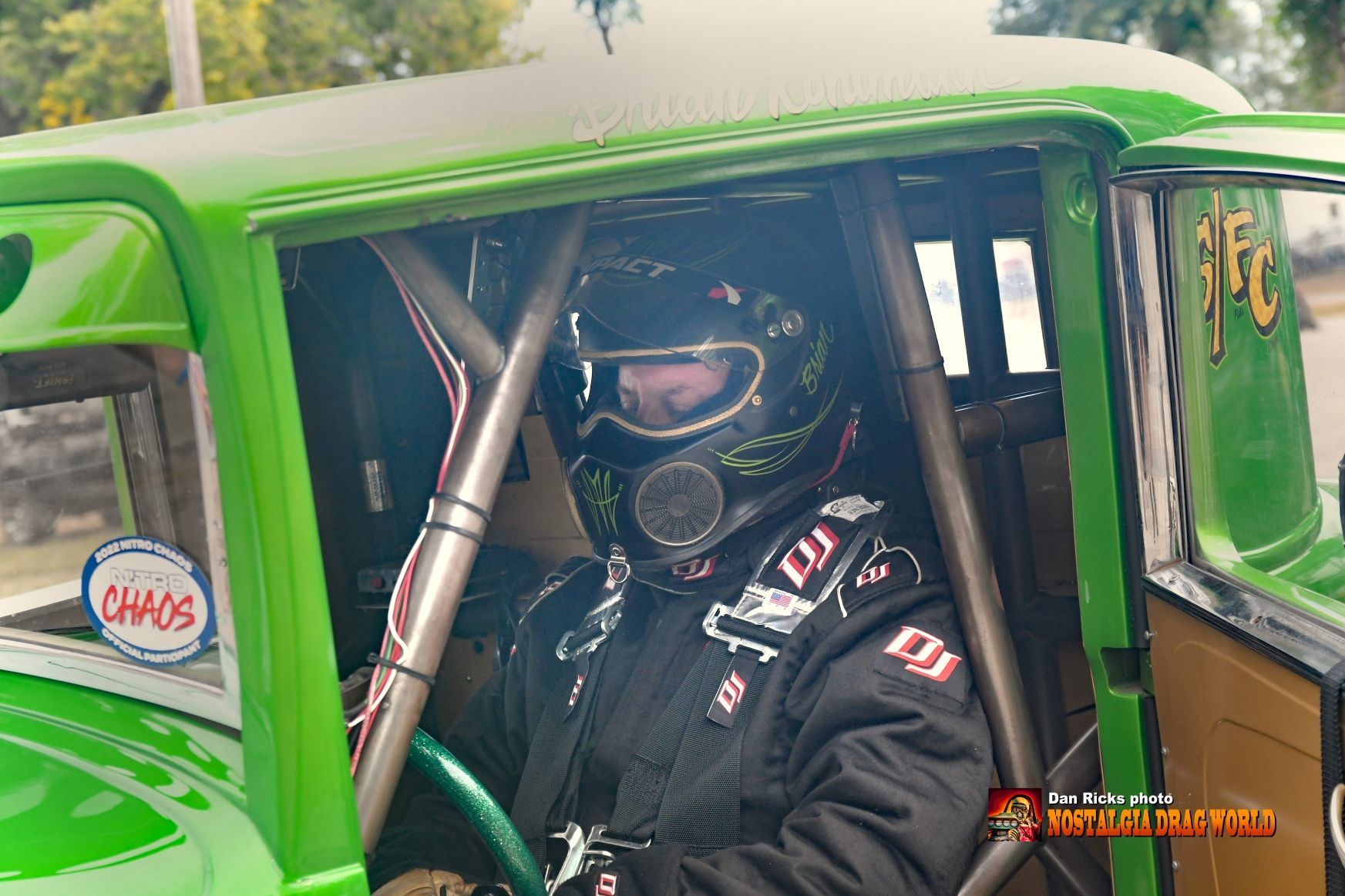 A man wearing a helmet is sitting in a green car.