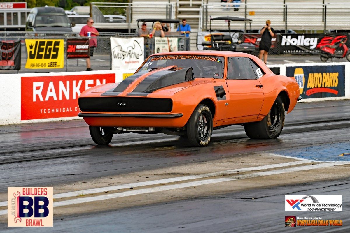 An orange car is driving down a race track with a sign that says ranken on it