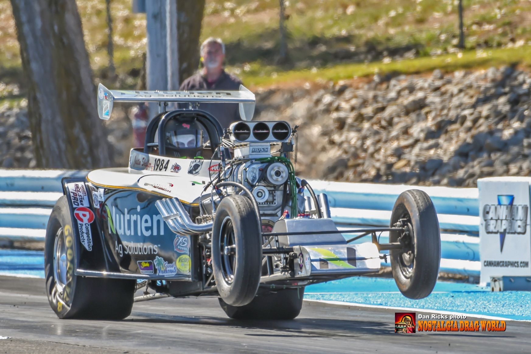 A drag race car is driving down a track.