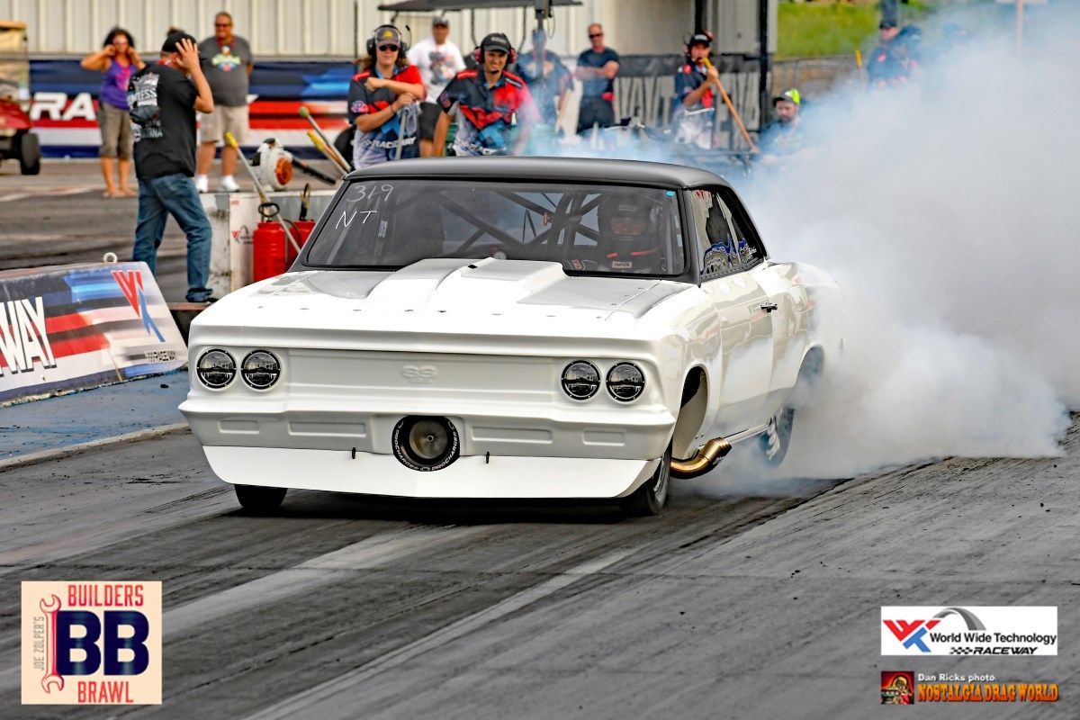 A white car is doing a burnout on a race track.