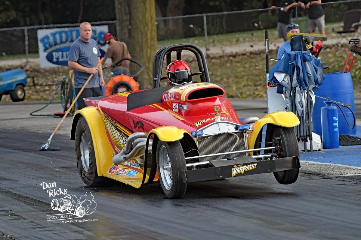 A red and yellow race car is driving down a track.
