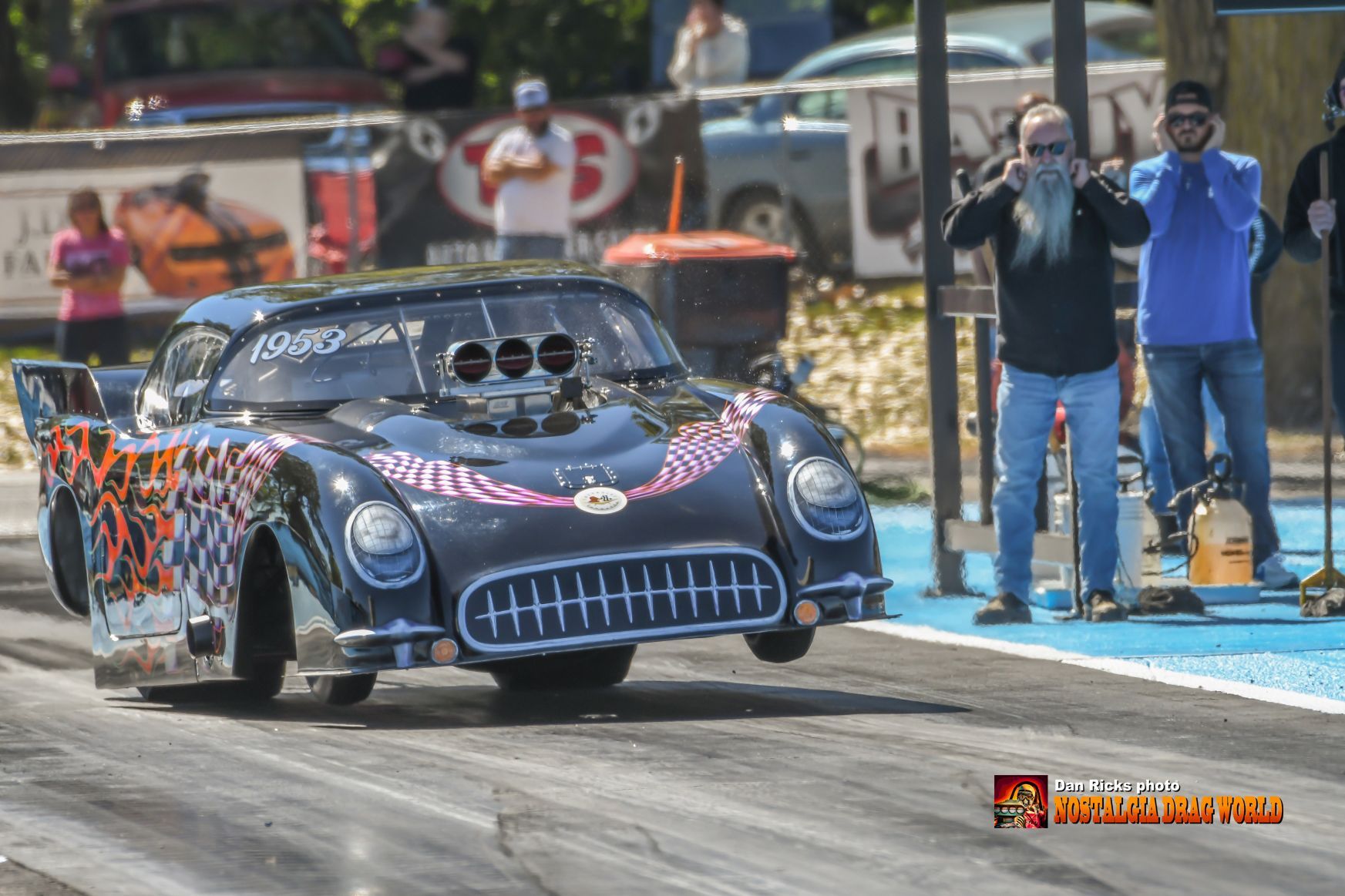 A black race car is driving down a race track.