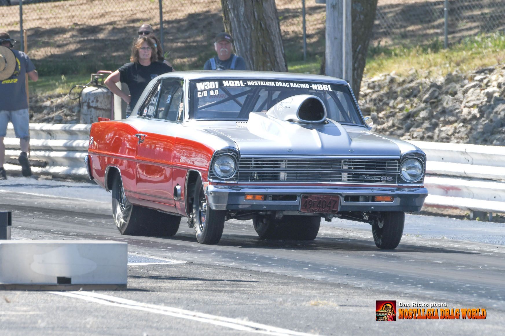 A red and silver car is driving down a race track.