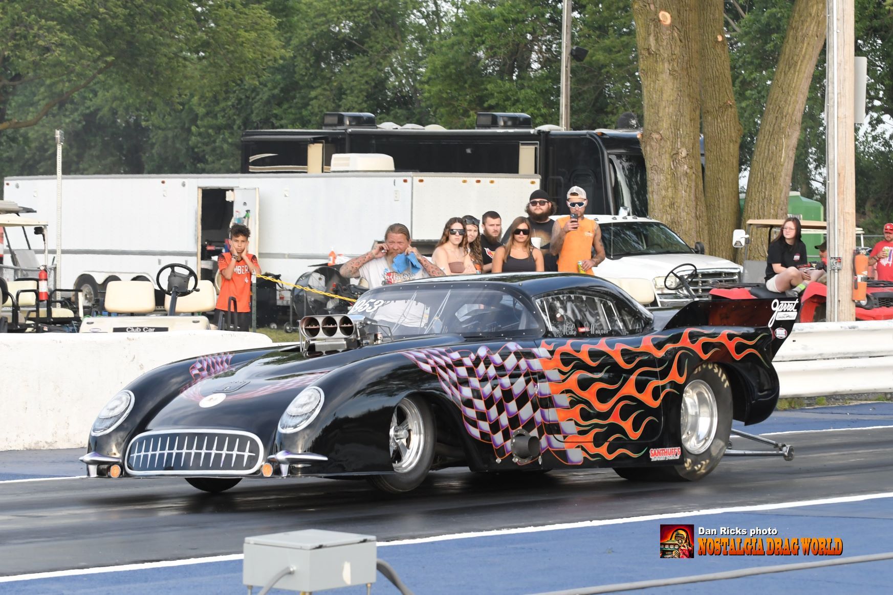 A race car with flames painted on it is on the track