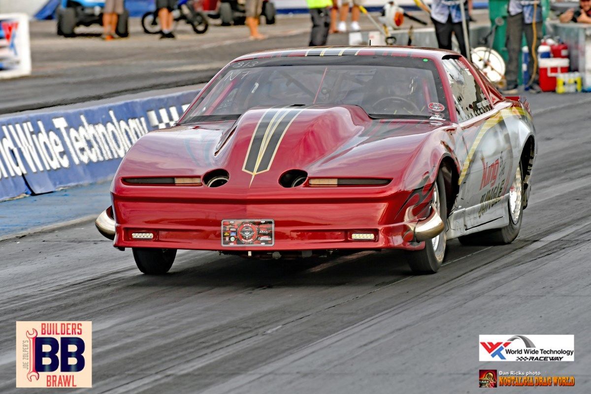 A red race car is driving down a track with a sign that says bb on it