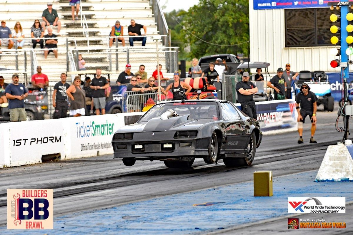 A black car is driving down a race track.