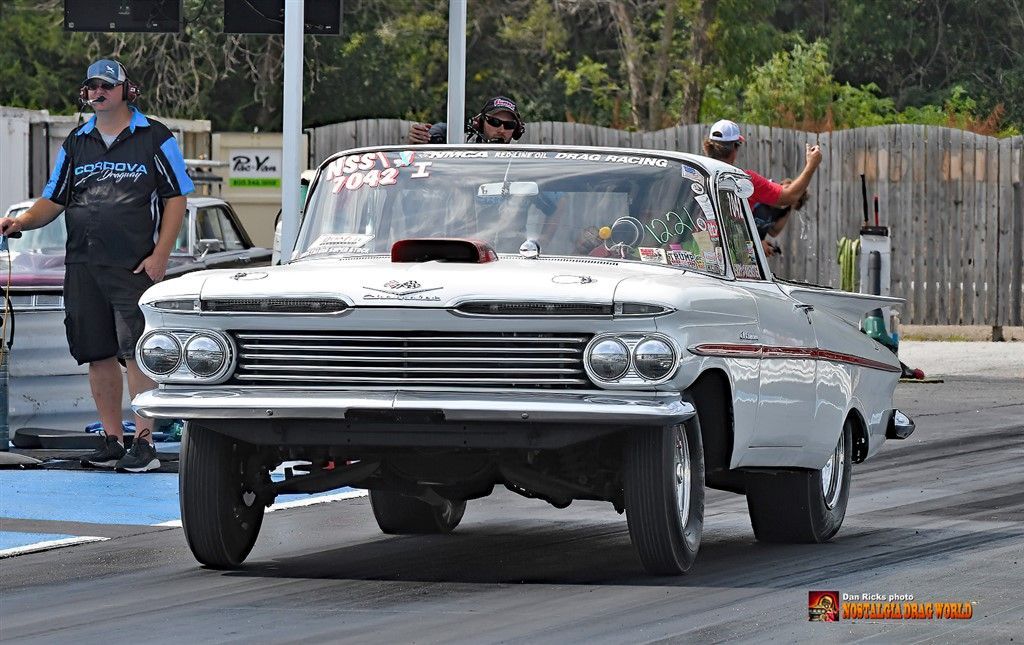 A white car is driving down a race track.