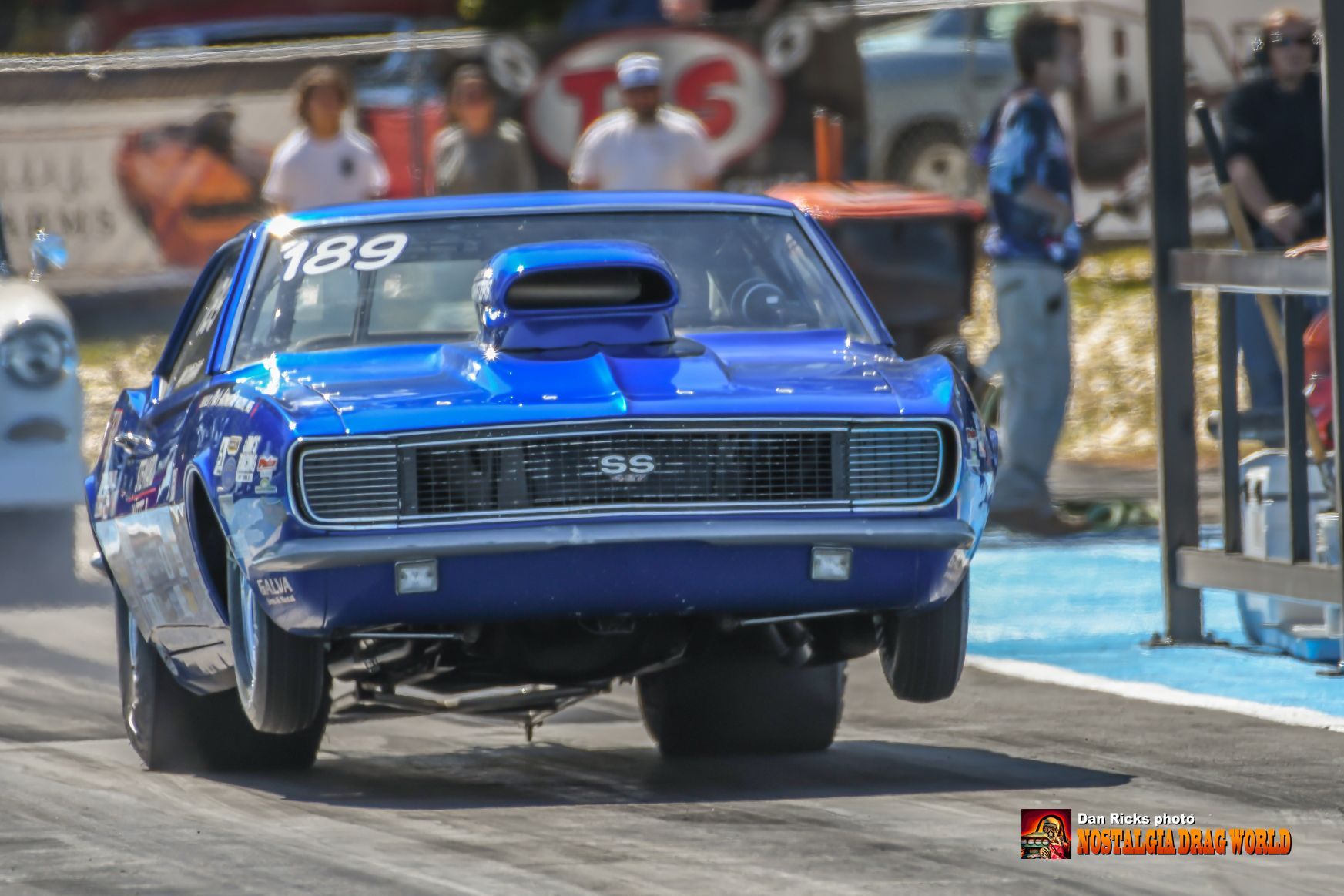 A blue car with the number 189 on the hood is driving down a race track.