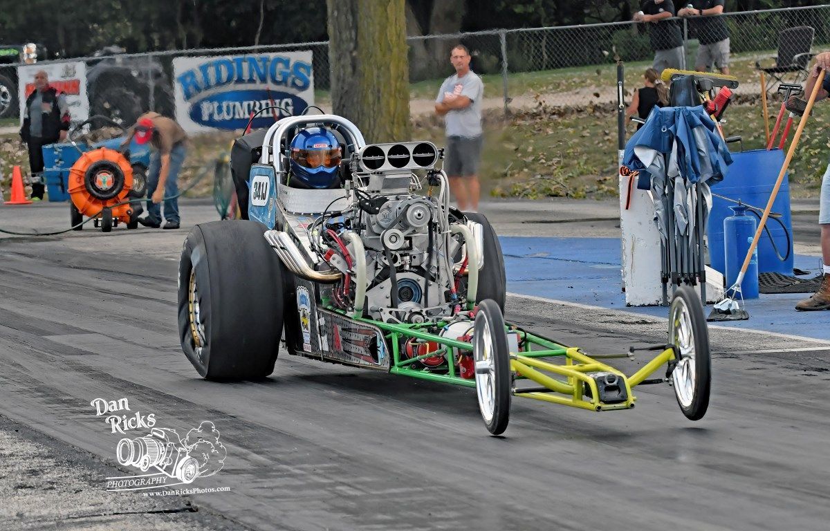A dragster is driving down a race track.